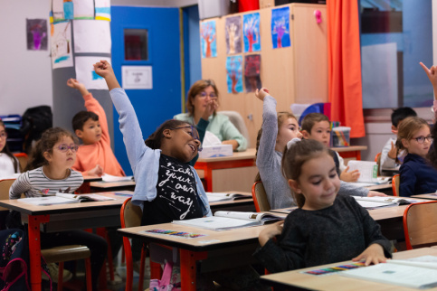 Des enfants de l'école en classe en train de lever la main
