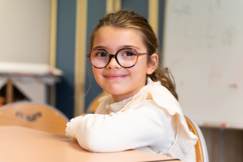 Une jeune élève qui sourit en regardant l'appareil